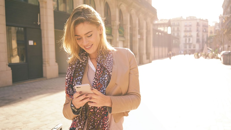 Woman checking phone whilst walking the street