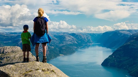 Gutt og kvinne ser utover fjordlandskap