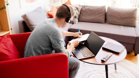 Mann sitter ved sofabord og jobber på laptop