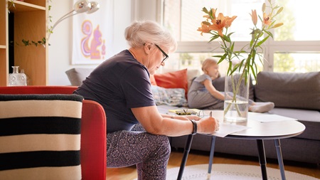 old woman signing papers at home